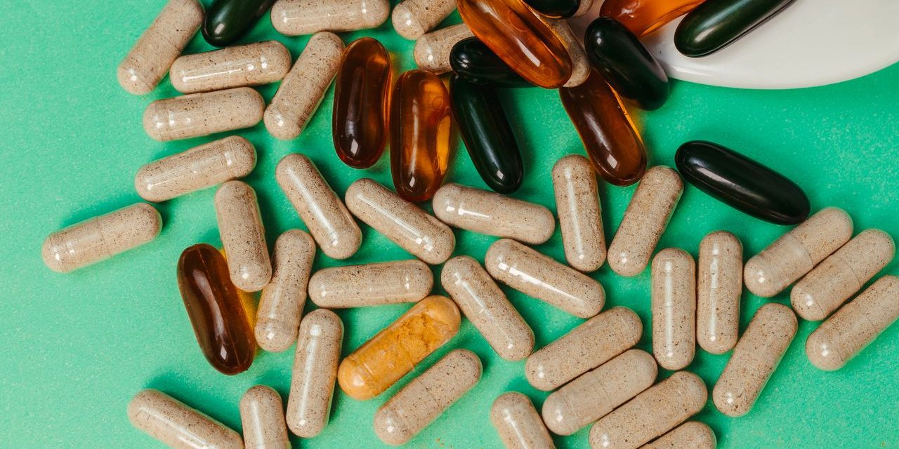 Various pills and capsules scattered on a green surface, symbolizing health supplements.