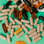 Various pills and capsules scattered on a green surface, symbolizing health supplements.