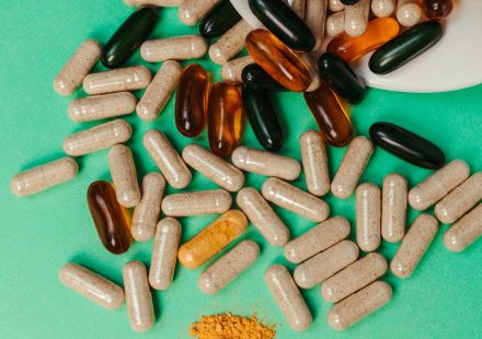 Various pills and capsules scattered on a green surface, symbolizing health supplements.