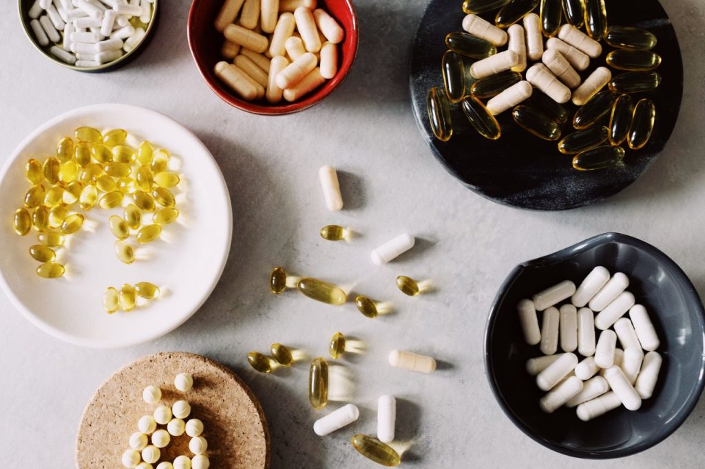 Various pills and supplements in bowls on a marble surface, ideal for healthcare contexts.