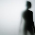 Blurred silhouette of a person behind frosted glass, creating a mysterious and artistic effect.