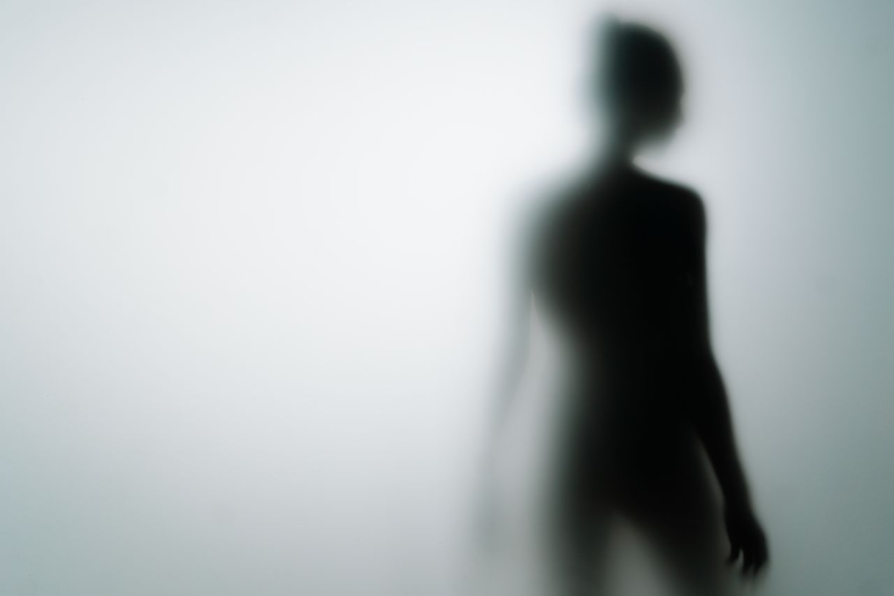 Blurred silhouette of a person behind frosted glass, creating a mysterious and artistic effect.