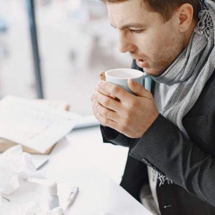 Comfortable office setting featuring a man in a scarf sipping coffee, embodying warmth and focus.